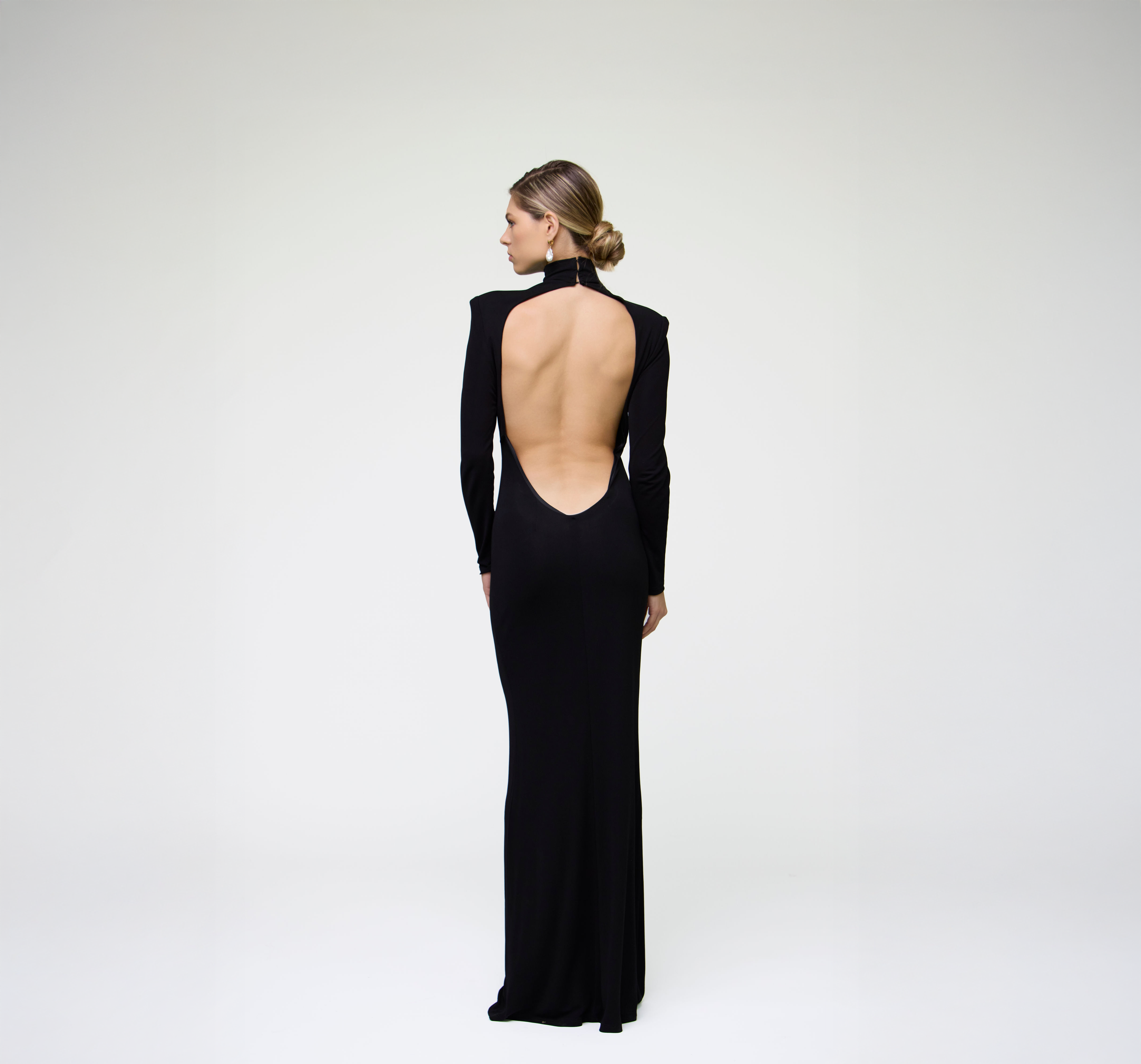 Back view of a black long sleeve maxi dress featuring an open back design on a model.