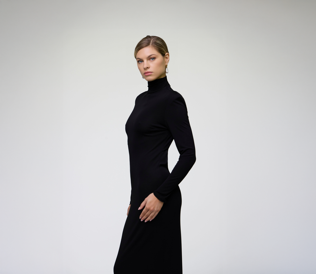 Side profile of a model wearing a black long sleeve fitted maxi dress.