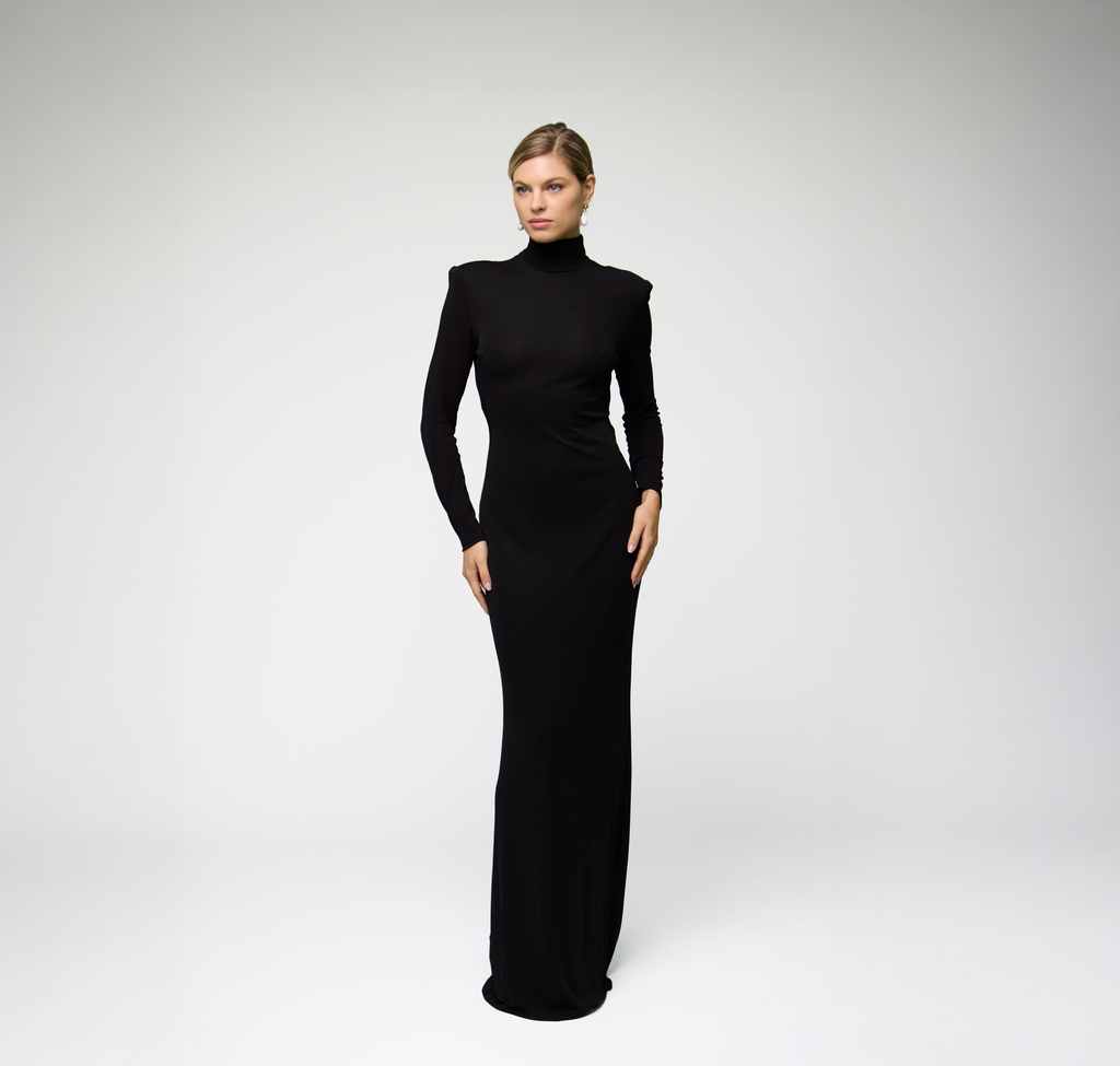 Model wearing a black long sleeve maxi dress with a fitted silhouette against a light grey background.
