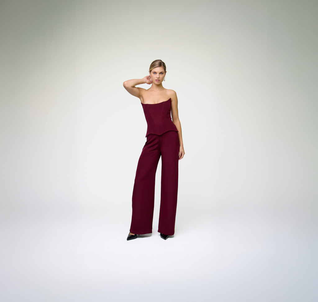 Model wearing ALICHE burgundy corset top with matching wide-leg trousers on white background