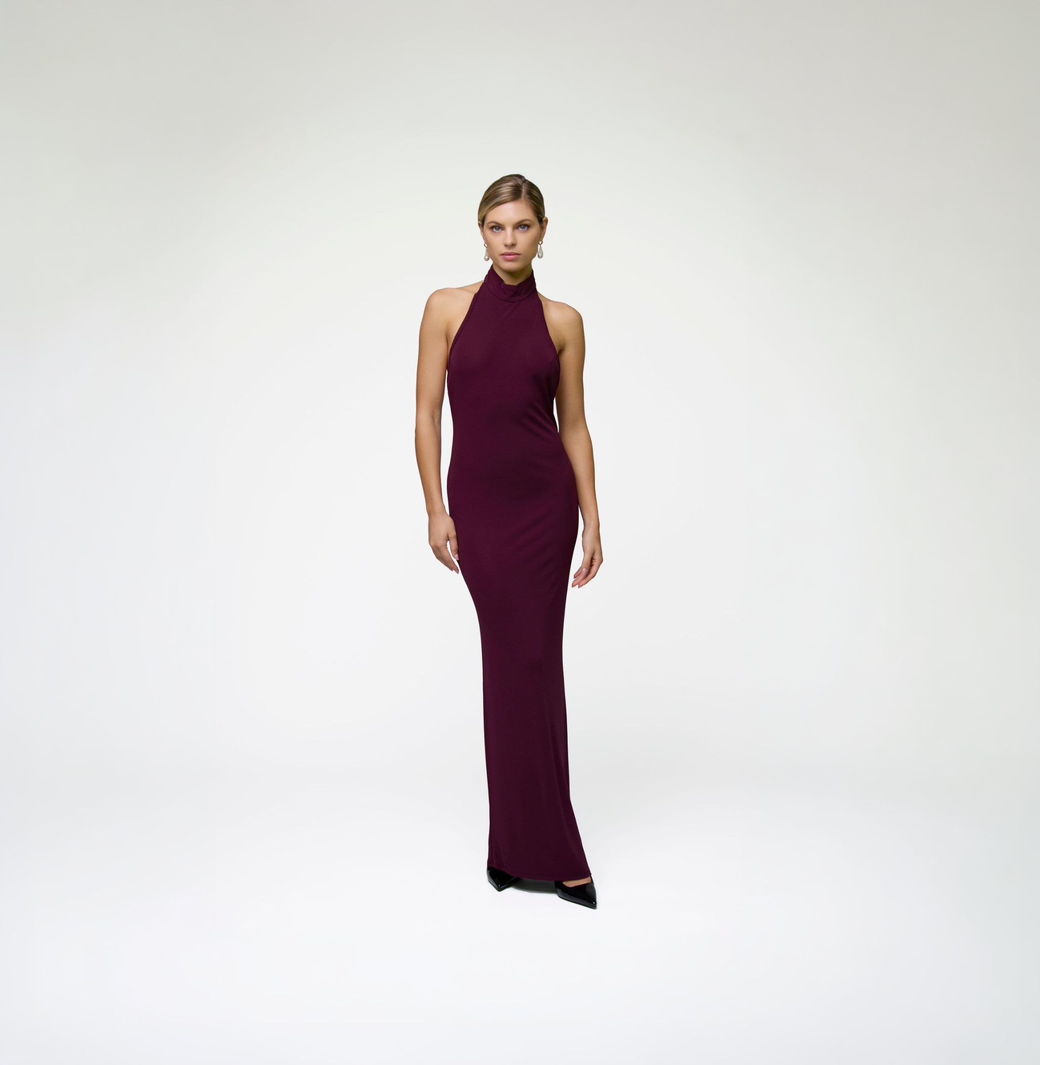 Model wearing ALICHE burgundy halter maxi dress on white background