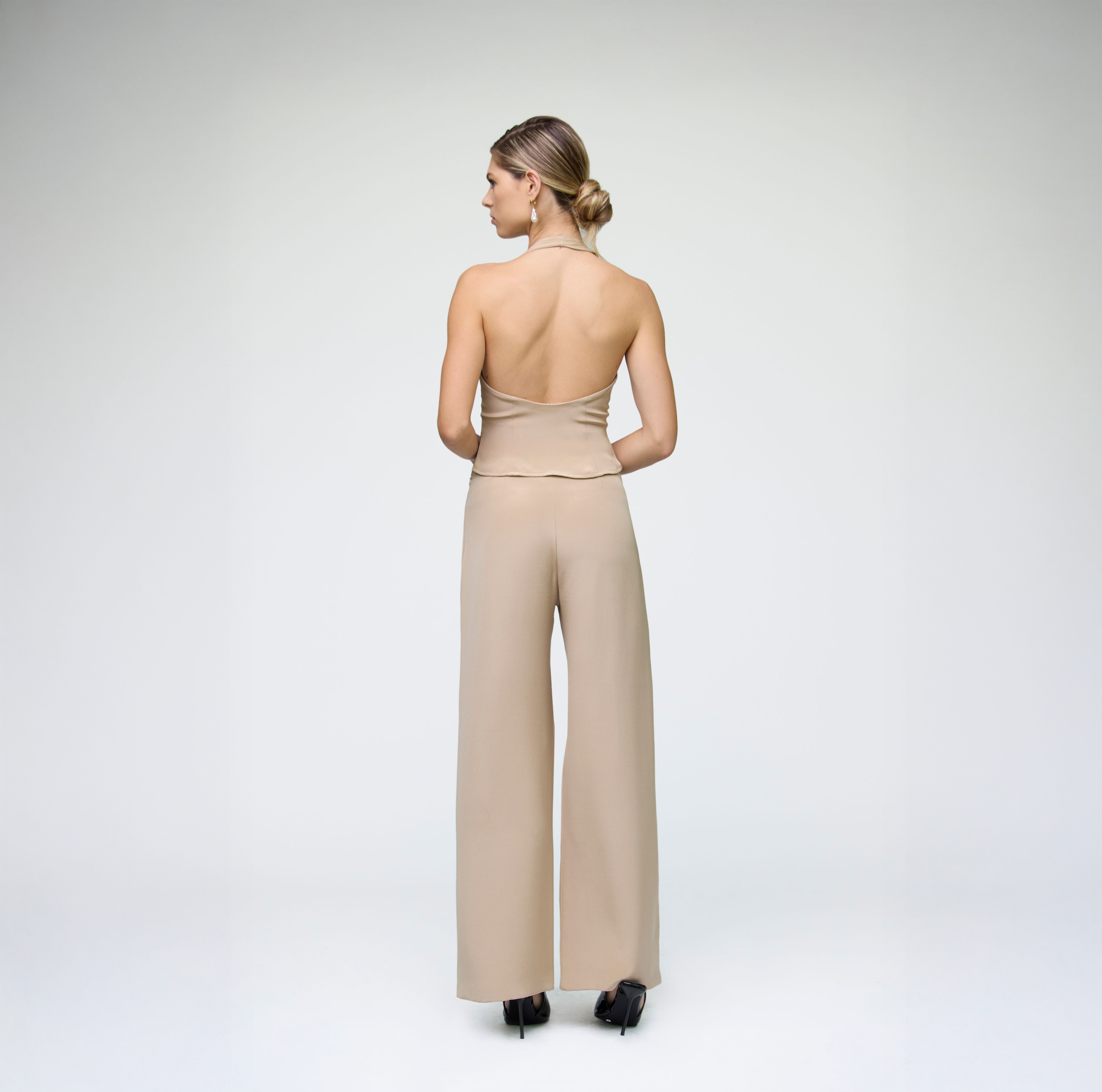 Back view of a sand halter vest styled with matching wide-leg trousers on a model.