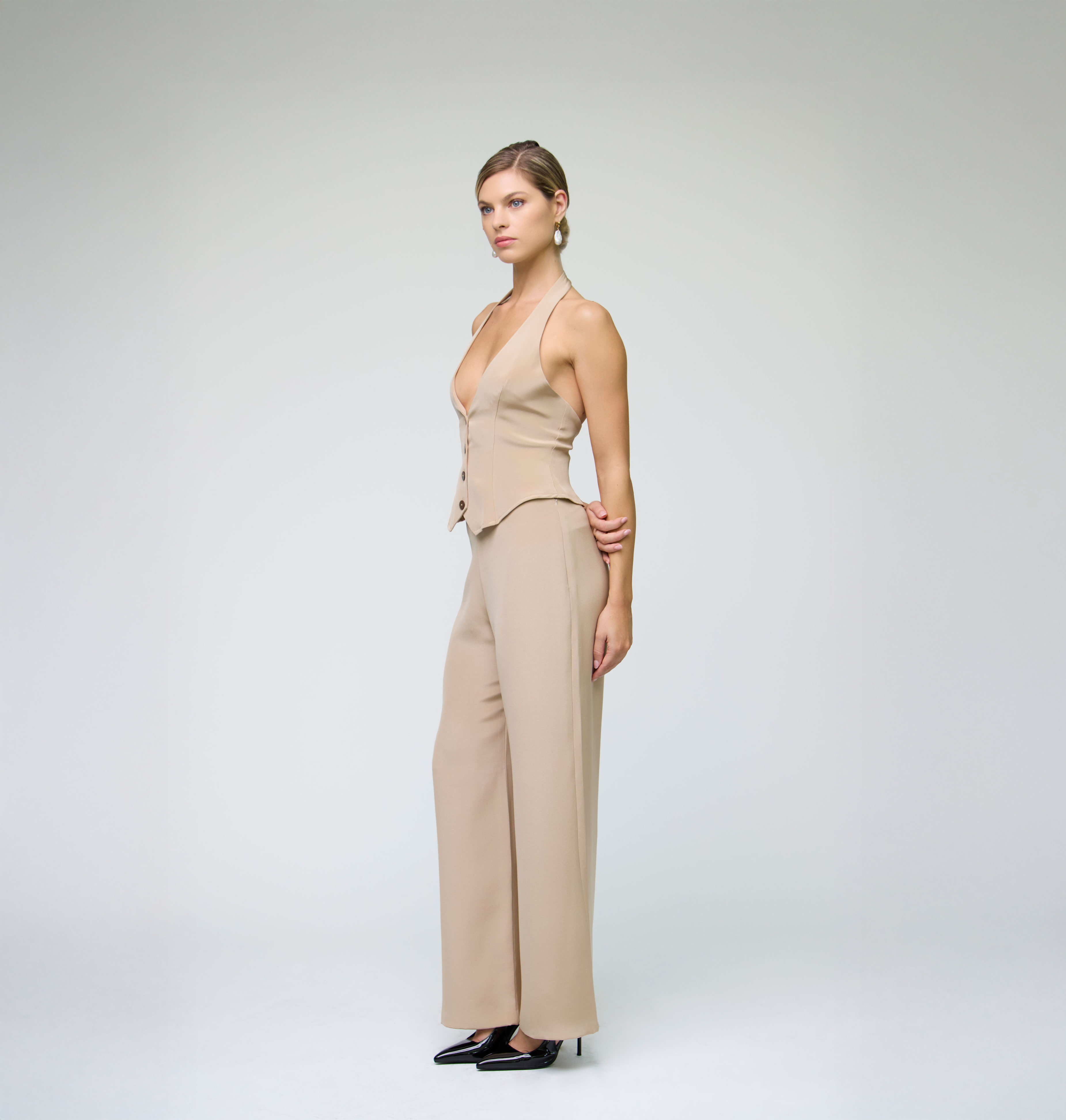 Side profile of a model wearing a sand halter vest styled with matching tailored trousers.