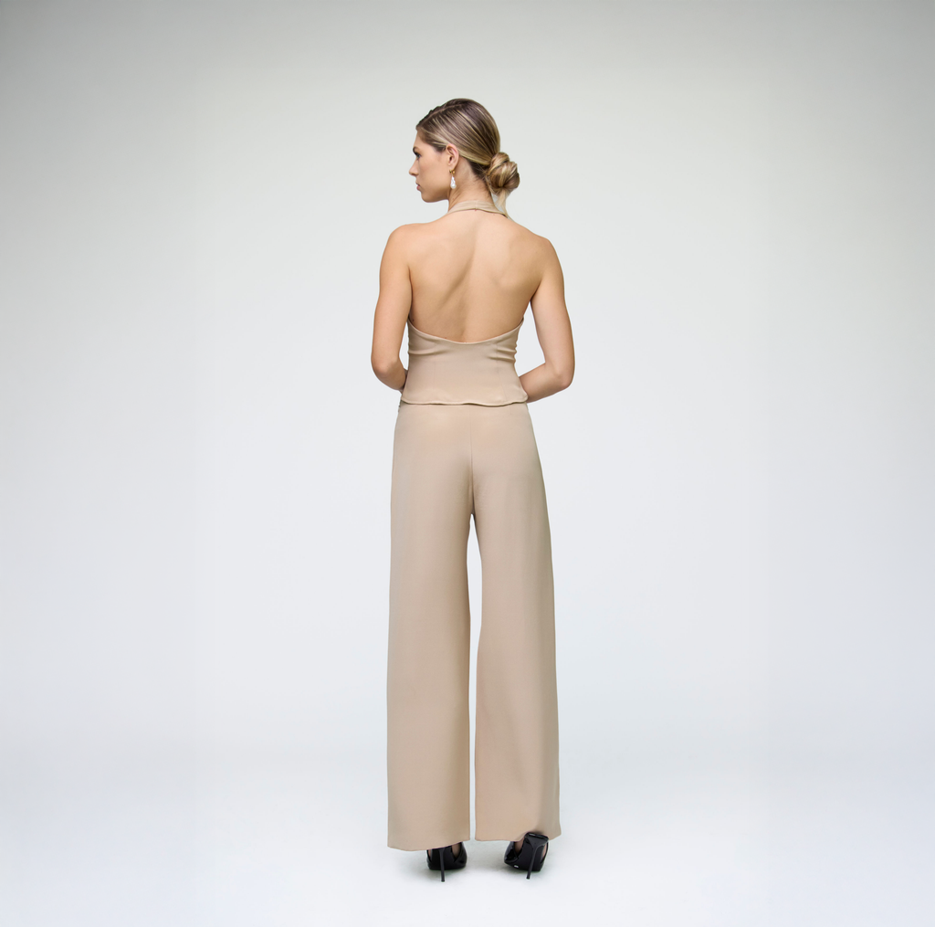 Back view of sand wide-leg trousers styled with a matching strapless top on a model against a light grey background.